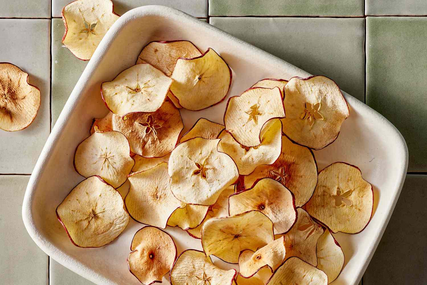 Crispy dehydrated apple slices arranged neatly in a white ceramic dish